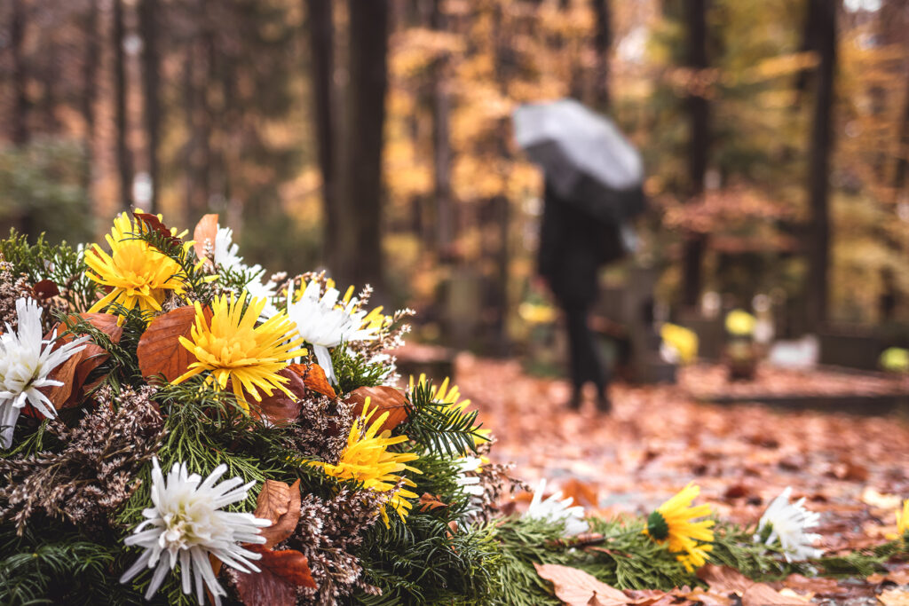 Flowers at tombstone. Defocused mourning woman holding flowers i