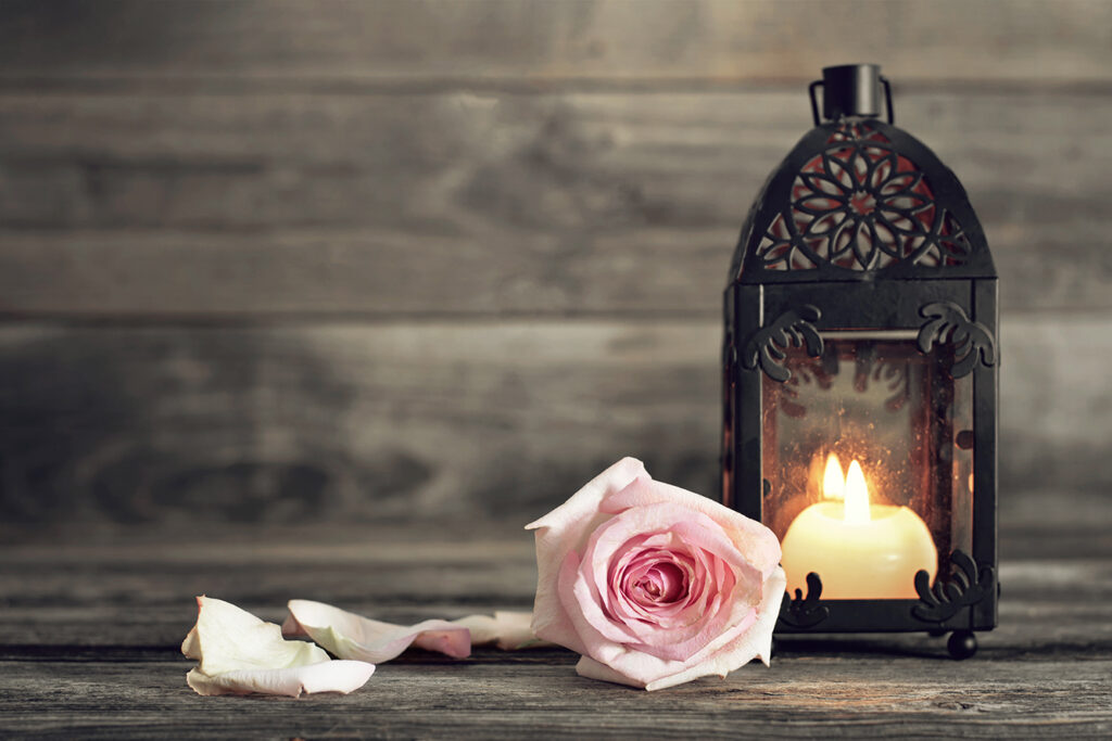 Memorial candle and rose on wooden background